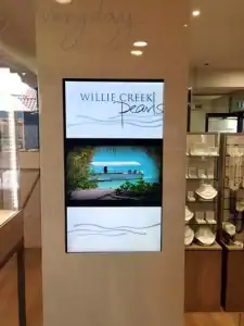 CCTV digital signage display showcasing Willie Creek Pearls in a retail store, highlighting security and communication technology integration.