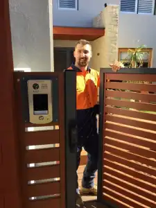 Security CCTV installation technician at residential gate with intercom system in modern home setting, showcasing advanced security and communication solutions, Tecsec Australia's trusted CCTV and security provider.