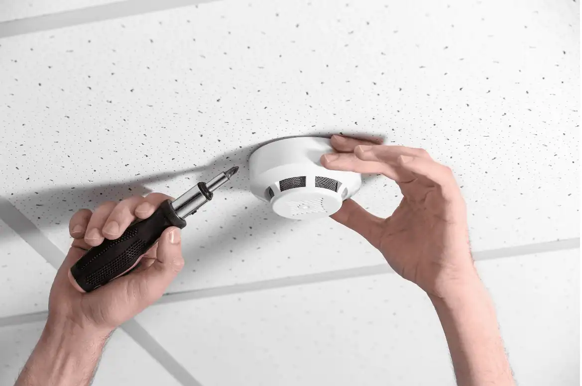 Clean installation of a smoke detector with a screwdriver, showcasing professional CCTV system setup and safety monitoring.